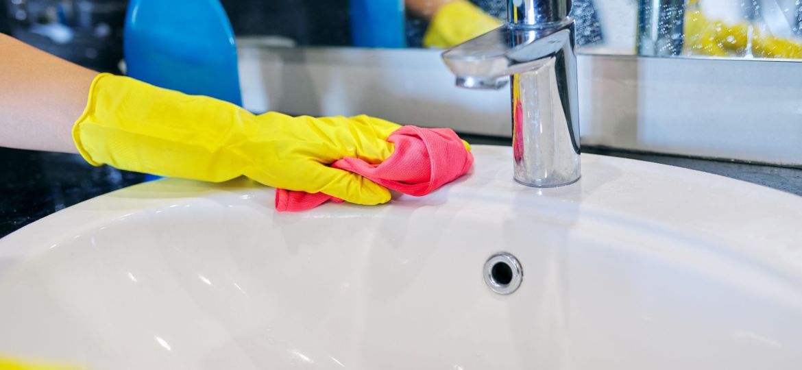 Close up of hands in gloves with detergent washing polishing washbasin
