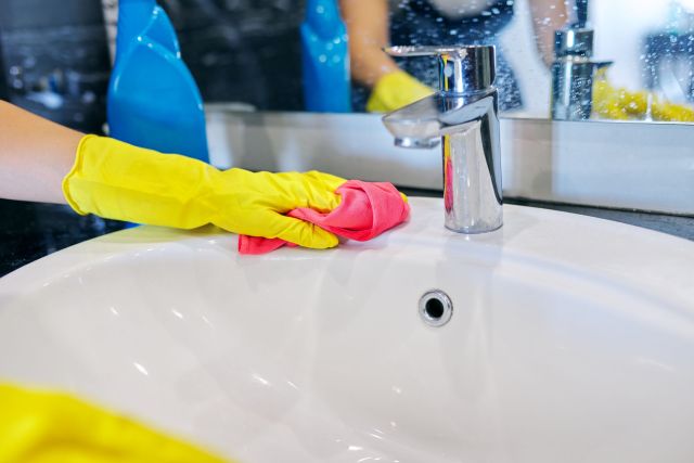 Close up of hands in gloves with detergent washing polishing washbasin